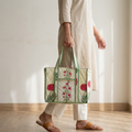 Person holding a floral embroidered tote bag in a minimal indoor setting